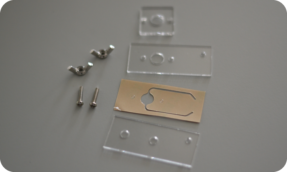 PMMA-PSA-PMMA Microfluidic Chips via Laser-Ablation and Assembly